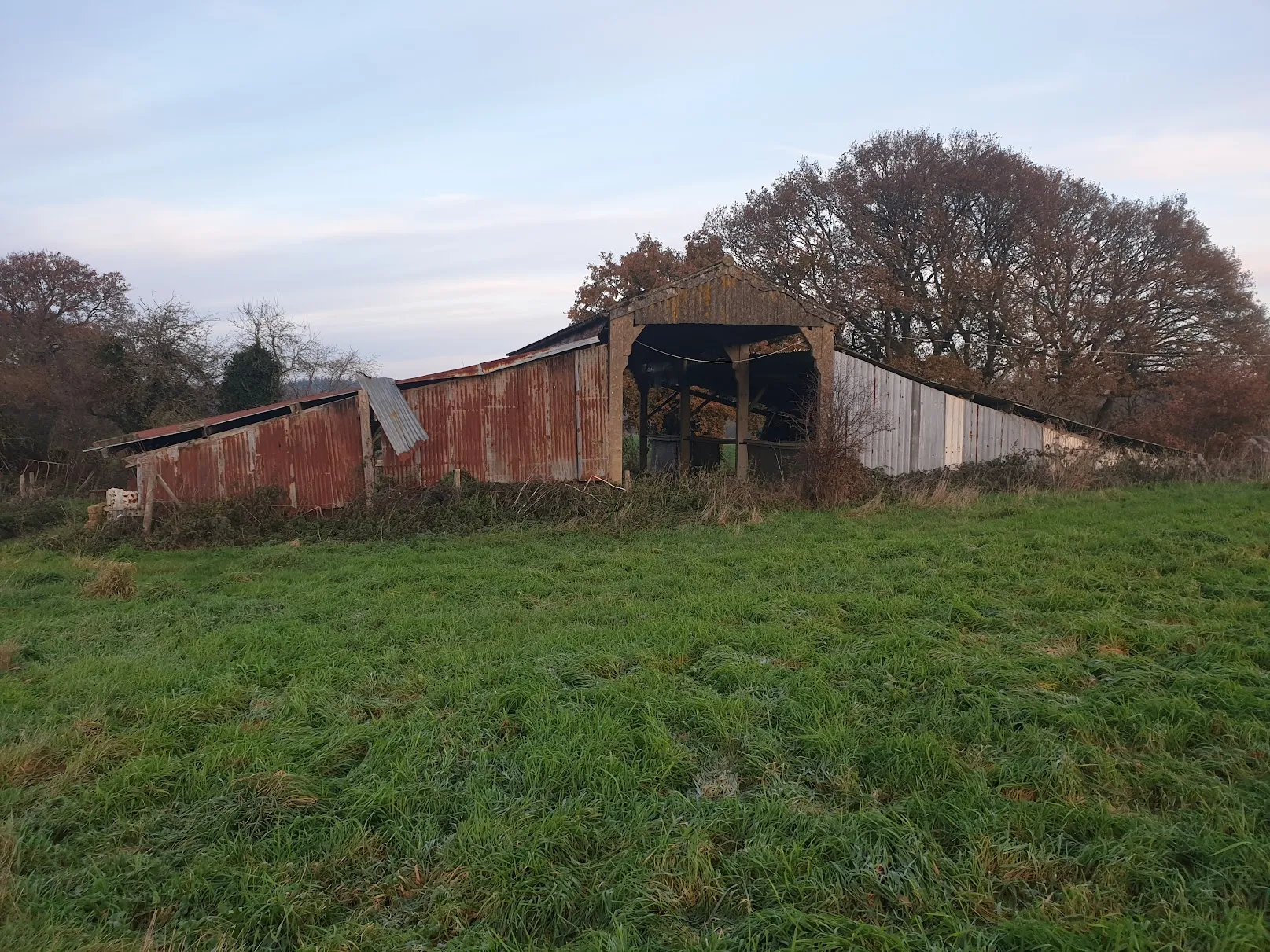 an old barn sits in a field of grass